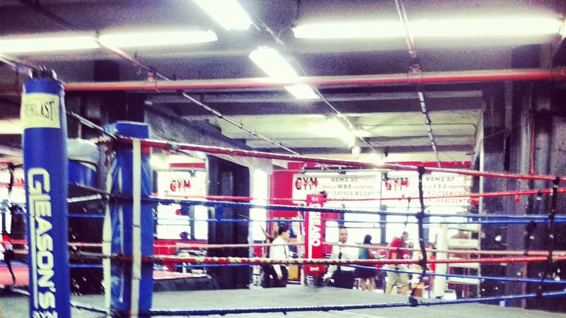 Ring de boxeo montado dentro del gimnasio Gleason's de Nueva York, con las cuerdas tensadas y la lona vacía.