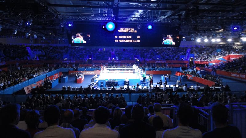 Combate de boxeo de los Juegos Olímpicos de Londres 2012 en el ExCeL Arena: ring iluminado en el centro de una arena oscura y llena de público, visto desde las gradas